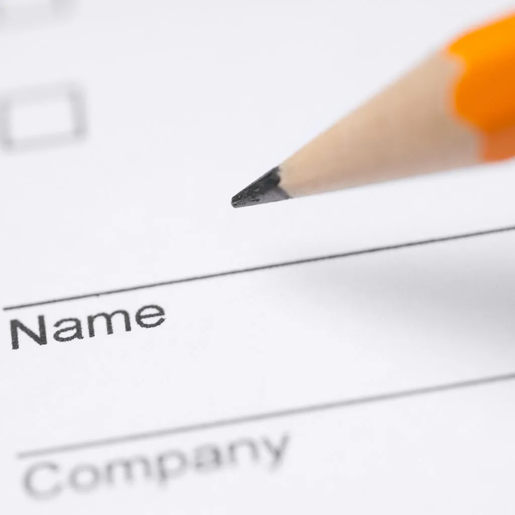 Potlood boven het veld ‘Name’ van een papieren formulier