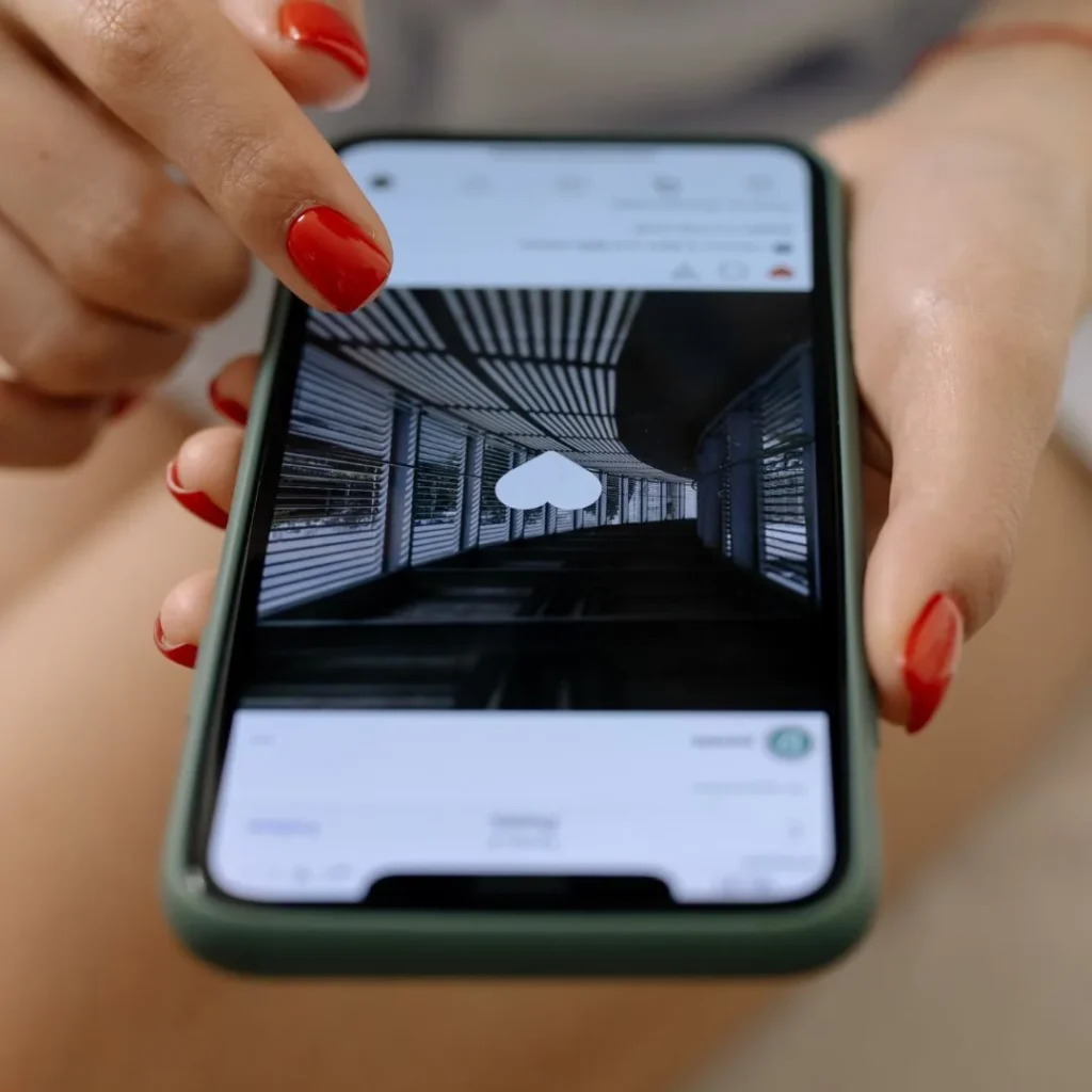 Doigt aux ongles rouges tapotant deux fois une photo pour l'aimer sur Instagram