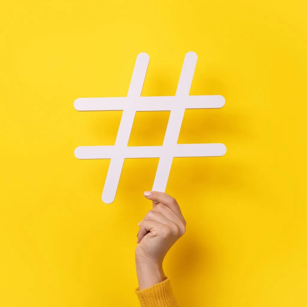 Hand met een groot wit hashtagsymbool op een gele achtergrond