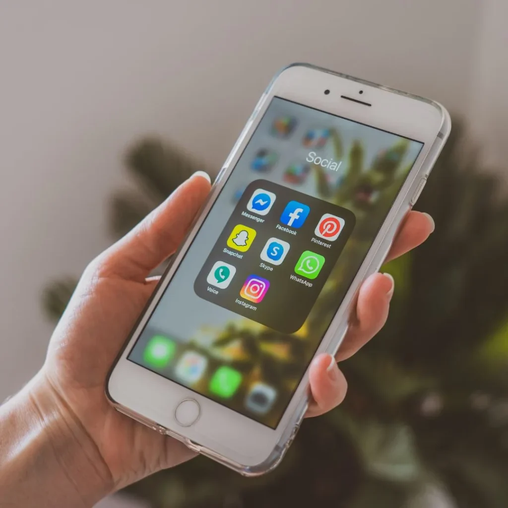 Main tenant un iPhone avec un dossier d'applications de réseaux sociaux ouvert