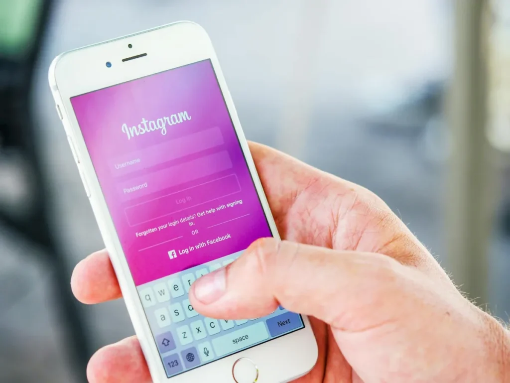 Mano sosteniendo un iPhone con la pantalla de inicio de sesión de Instagram