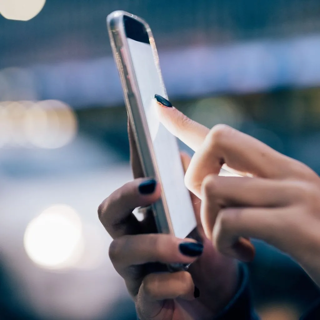 Vinger tikt 's avonds op straat op een smartphonescherm