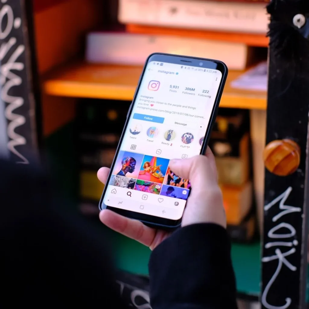 Main tenant un smartphone ouvert sur un profil Instagram