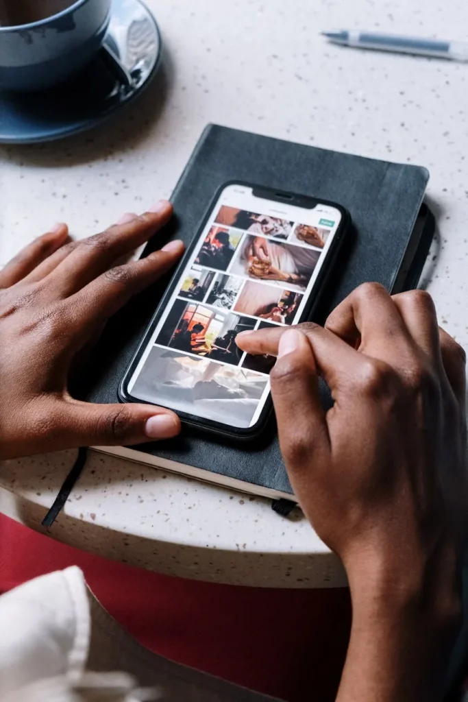 Manos deslizando fotos en un móvil apoyado sobre una libreta negra