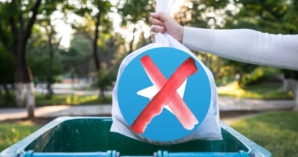 Trash bag with a crossed-out Telegram logo thrown into a dumpster