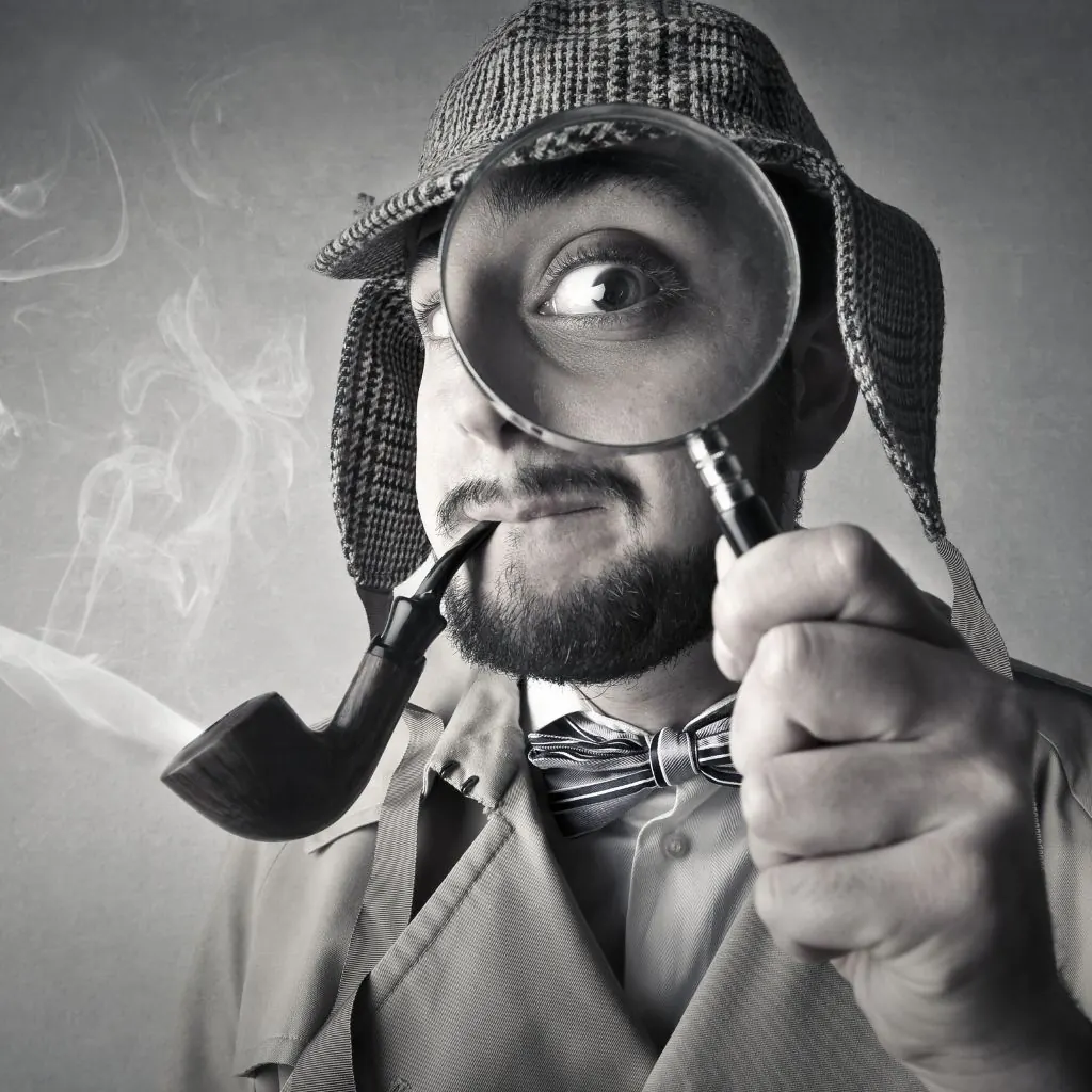 Man verkleed als detective die door een vergrootglas kijkt
